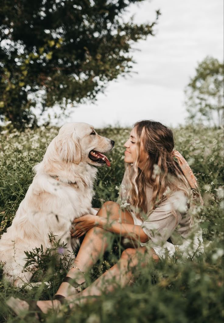 Mujer y perro mirándose con cariño en un campo de flores, símbolo del vínculo de alma entre humano y animal